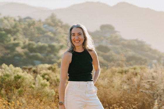 Alyssa standing in a field with sunlight and hills behind her, as she starts her personal journey through perimenopause.