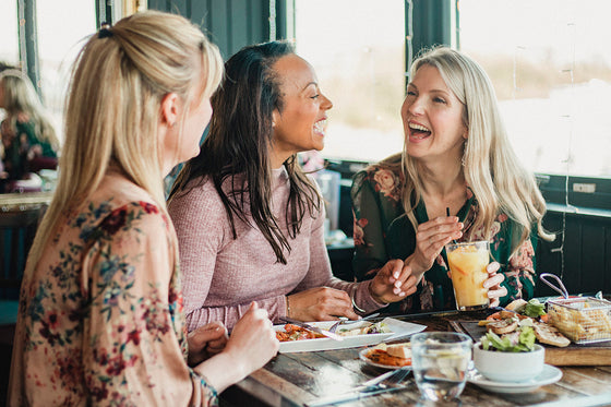 three friends going through menopause enjoying food together and sharing their menopause stories