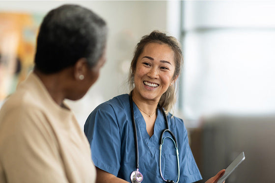 A menopause specialist smiles at a patient, creating a comfortable and supportive environment for discussing health concerns. 