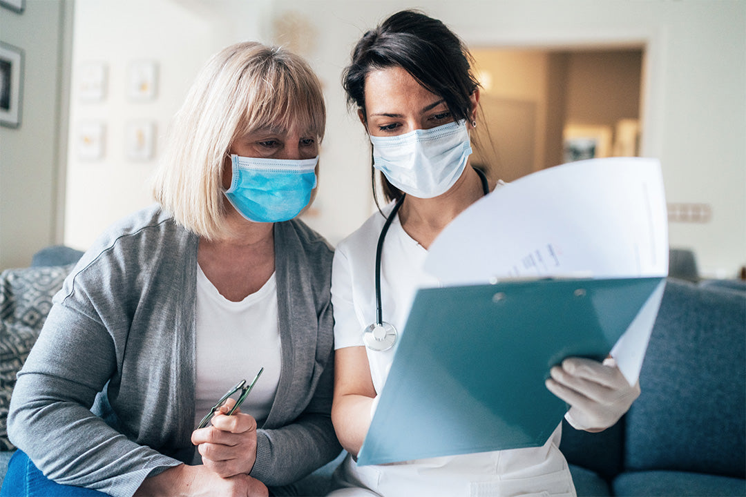 A doctor wearing a face mask reviews menopause treatment options with a patient