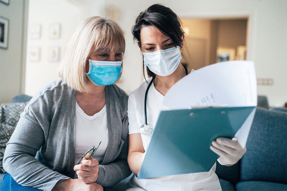 A doctor wearing a face mask reviews menopause treatment options with a patient