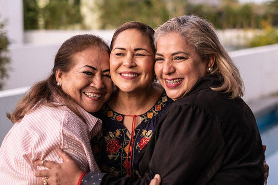 A warm embrace between three woman representing different generations, symbolizing the shared experience and support that women can find throughout the stages of menopause