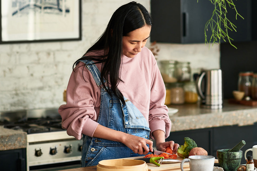 Perimenopausal woman standing in her kitchen preparing a healthy meal for menopause using fresh spring ingredients