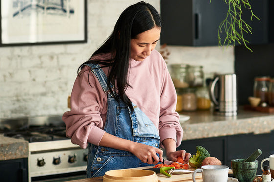 Perimenopausal woman standing in her kitchen preparing a healthy meal for menopause using fresh spring ingredients
