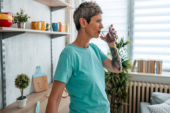 Woman in perimenopause sipping water throughout the day to help stay hydrated during menopause