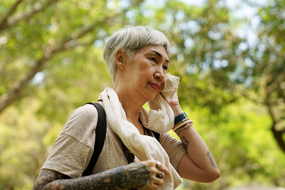 An older woman standing outside experiencing hot flashes after menopause
