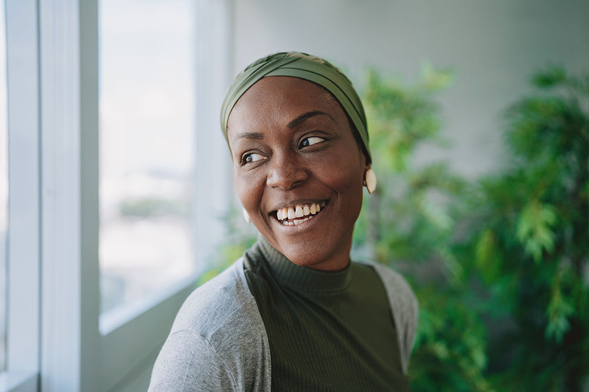 A woman going through the hormonal changes during perimenopause standing near a bright window 