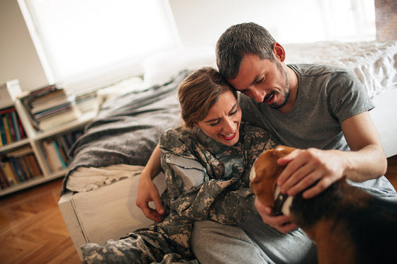 A couple sits close together at home, sharing a quiet moment and petting their dog, showing emotional intimacy during menopause.