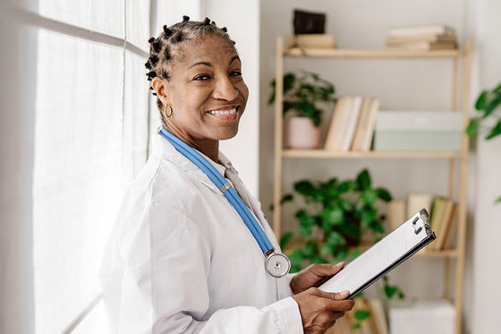 A confident and friendly Black female menopause doctor, is holding a patient chart. Medical professionals can provide support and guidance through menopause.