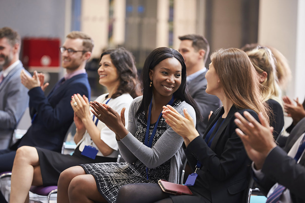 Audience seated at a professional conference applauding during a presentation