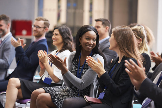 Audience seated at a professional conference applauding during a presentation